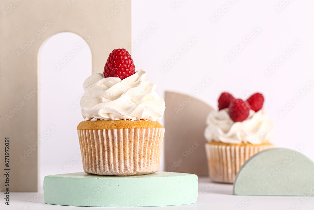 Decorative stand with tasty raspberry cupcakes on grey background