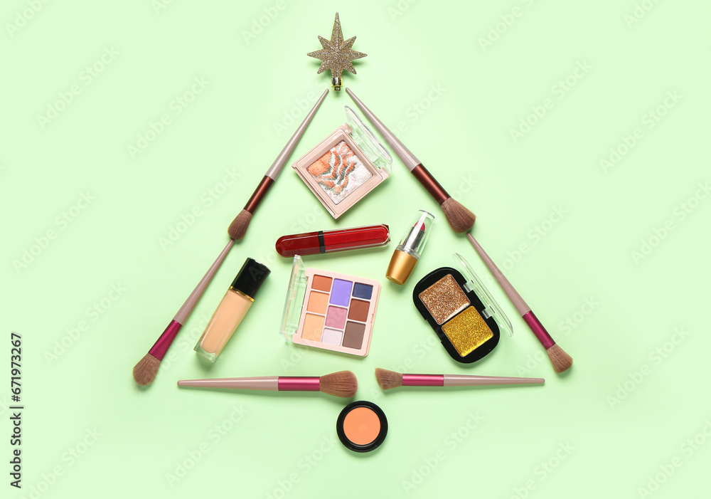 Christmas tree made of makeup products and decor on green background