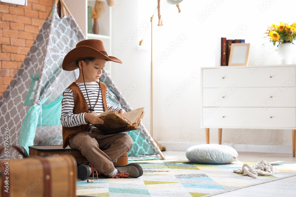 Cute little cowboy with adventure book at home