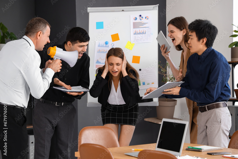 Young businesswoman suffering from noisy colleagues in office