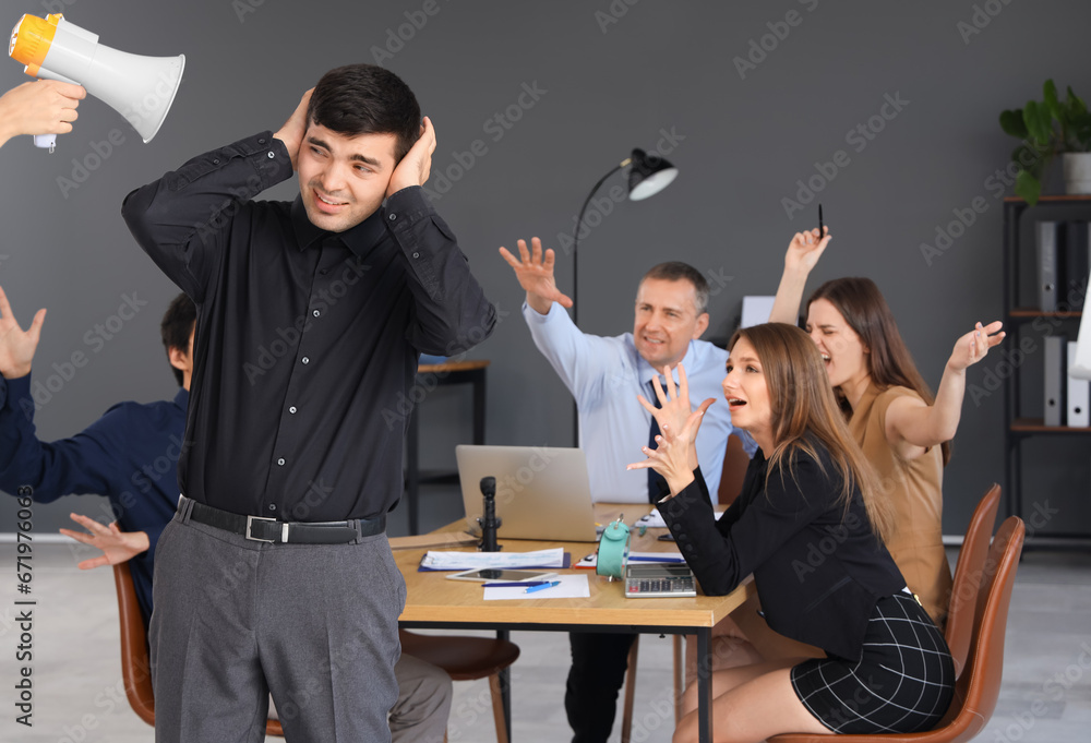 Young businessman suffering from noisy colleagues in office