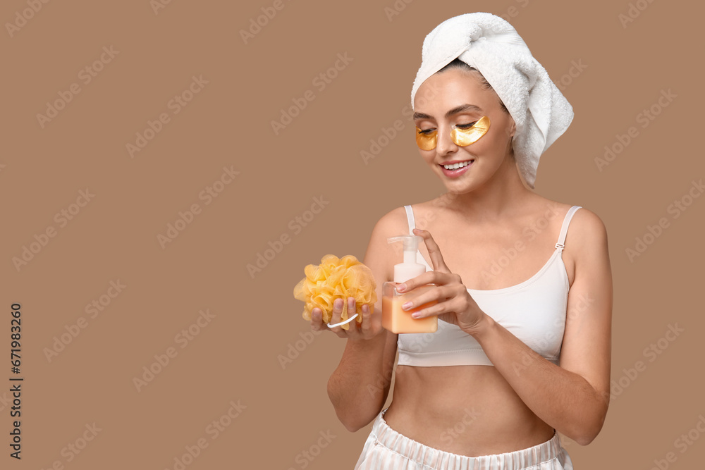 Young woman with shower gel and loofah on brown background