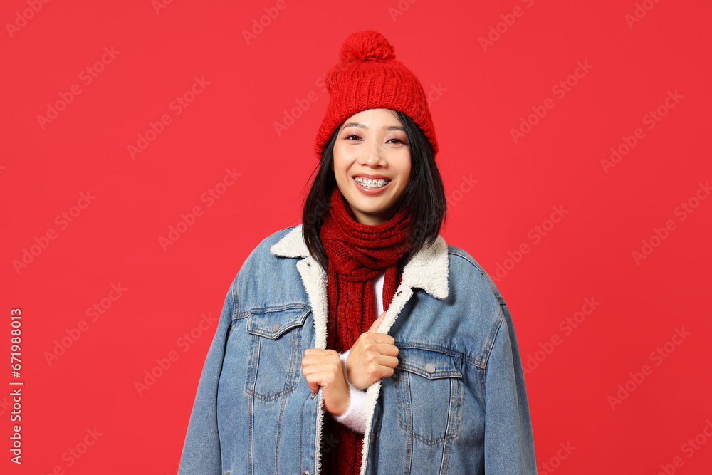 Young Asian woman in winter clothes on red background