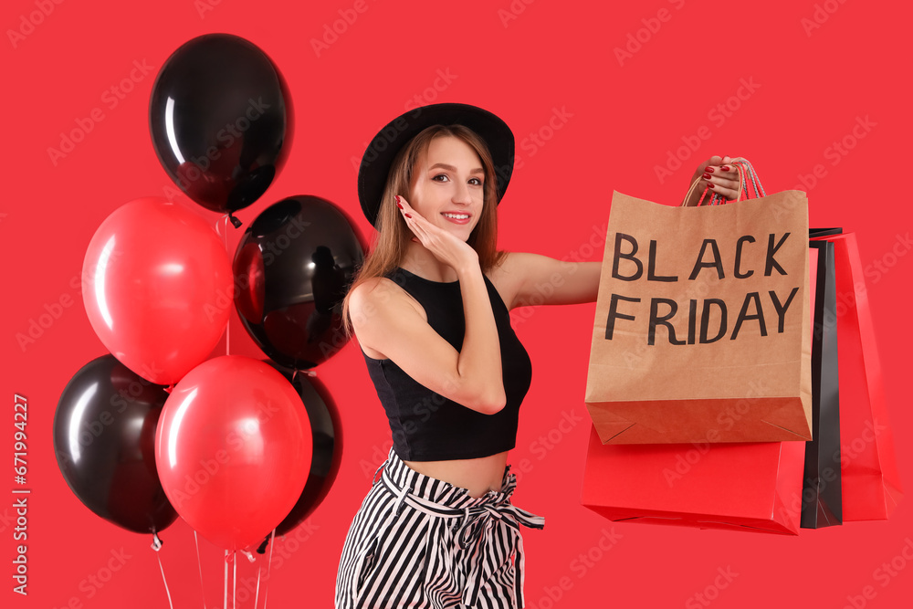 Beautiful young woman with balloons and shopping bags on red background. Black Friday sale