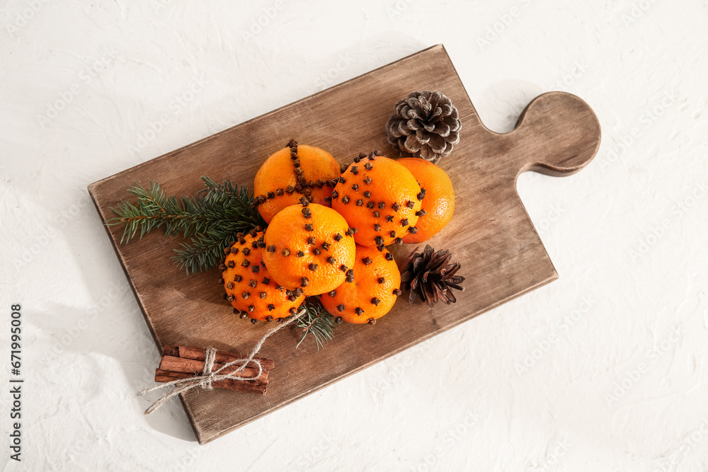 Wooden board with pomander balls and cinnamon on white background