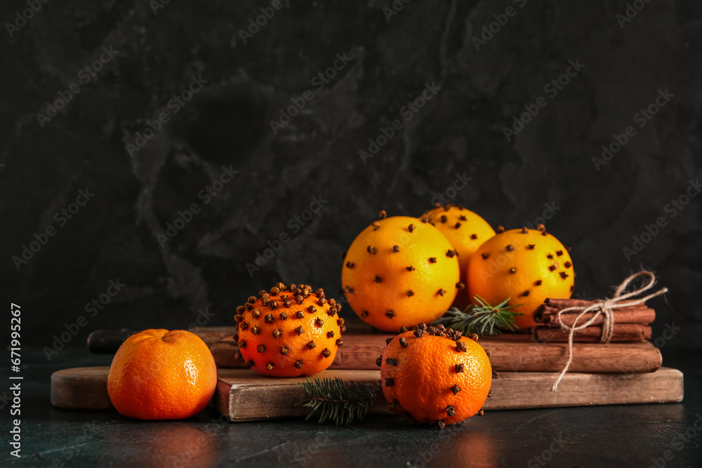 Wooden board with pomander balls and cinnamon on dark background