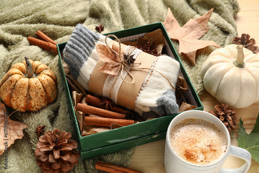 Beautiful composition with warn socks, cup of coffee and pumpkins on beige wooden background