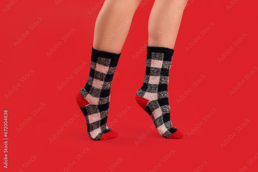 Legs of young woman in warm socks on red background