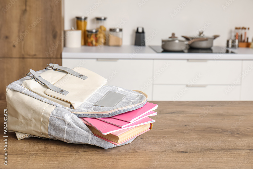 Stylish school backpack with stationery on table in kitchen