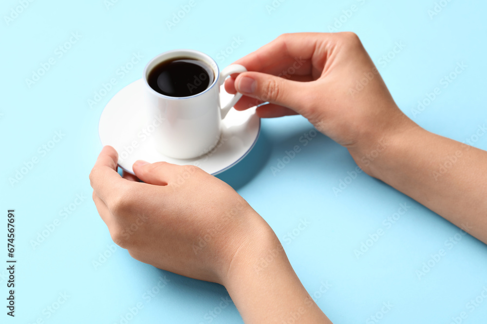 Woman holding cup of hot coffee on blue background