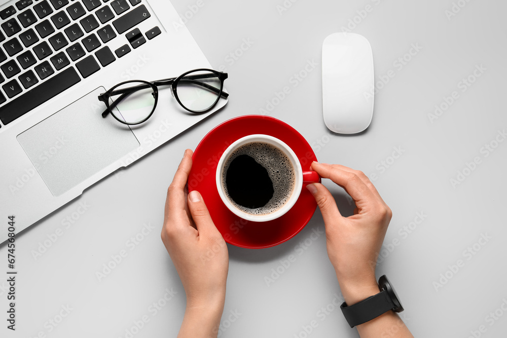 Female hands with cup of hot coffee and eyeglasses on white background