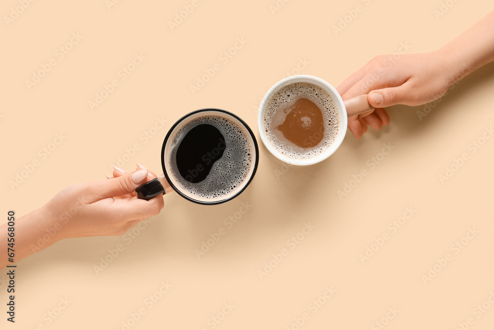 Women holding cups of hot coffee on yellow background