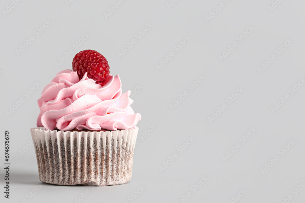 Tasty raspberry cupcake on grey background