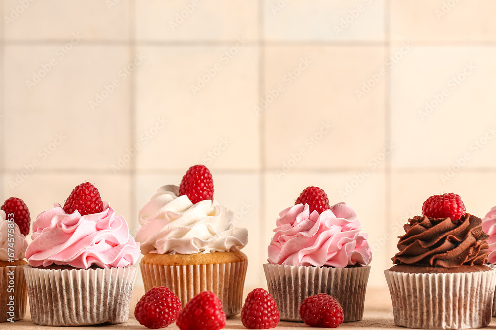 Tasty cupcakes with raspberries on table