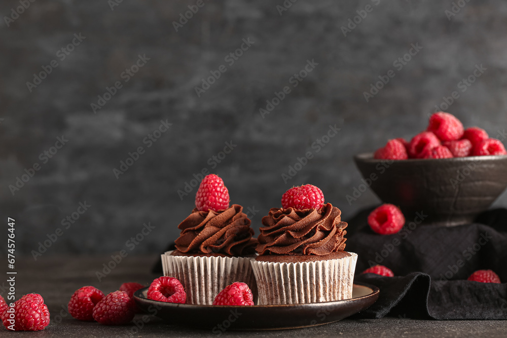 Plate of tasty chocolate cupcakes with raspberries on black background