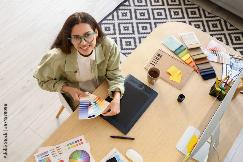 Female interior designer working with color palettes at table in office, top view