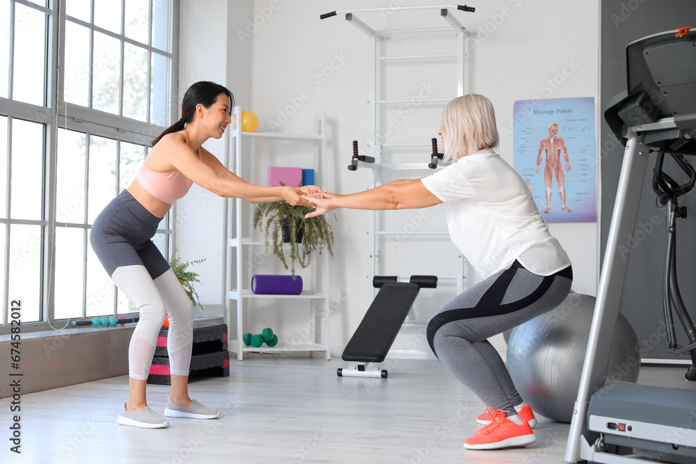 Mature woman training with therapist in rehabilitation center