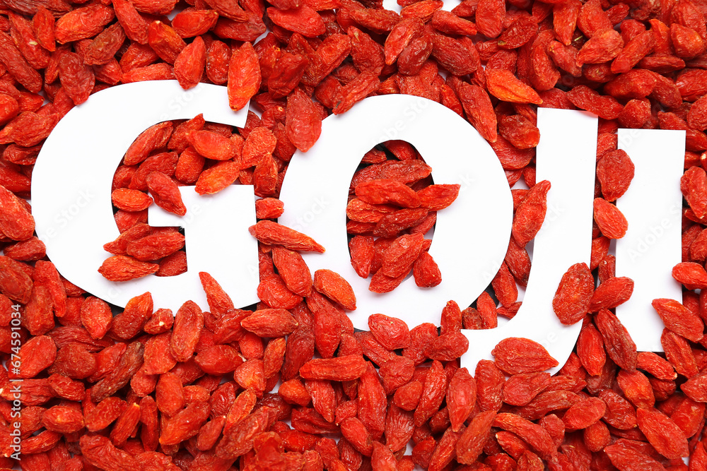 Word GOJI and red dried berries as background