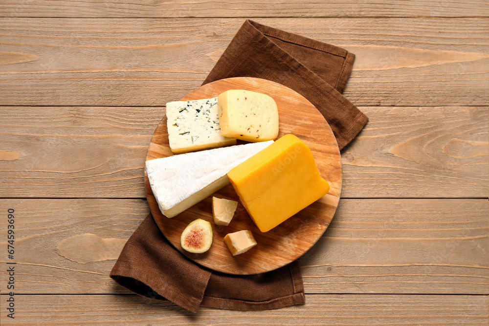 Board with tasty cheese on wooden background