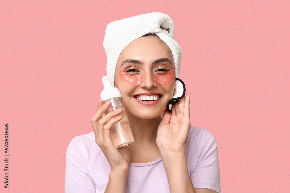 Young woman with reusable cotton pad and cleanser on pink background, closeup