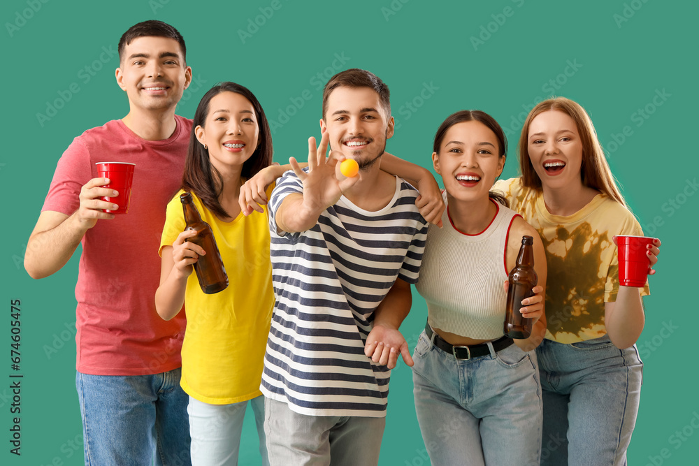 Group of young friends with beer and ball on green background