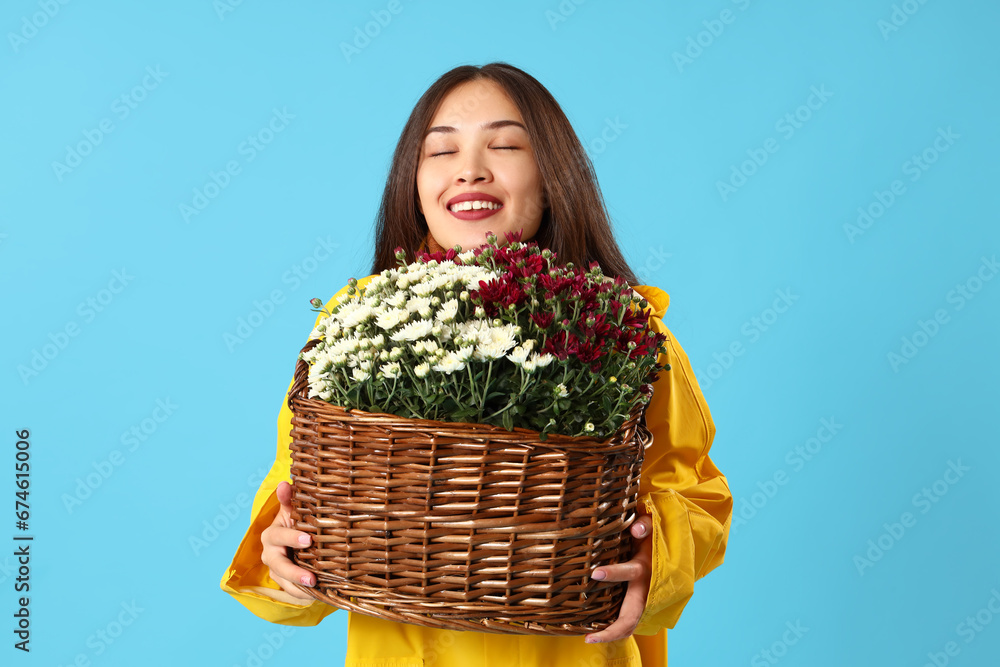 Young Asian woman with chrysanthemum flowers on blue background