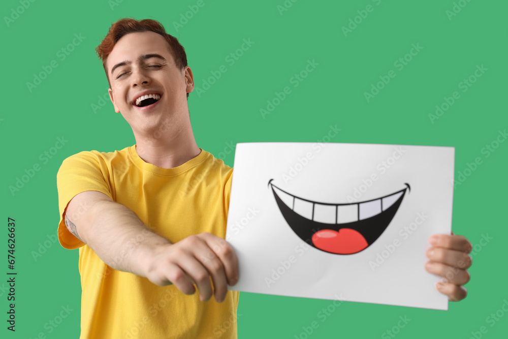 Young man with paper smile on green background, closeup