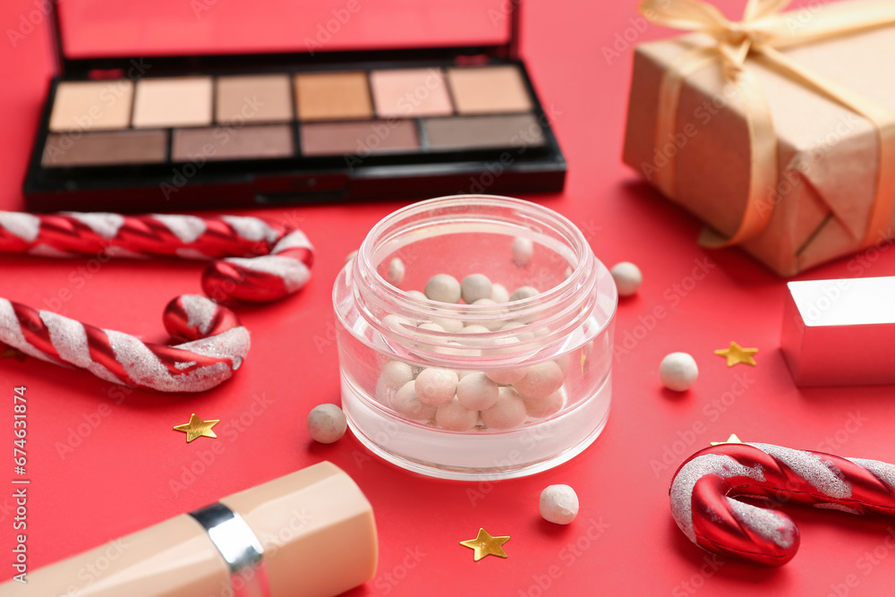 Makeup products and Christmas decor on red background, closeup