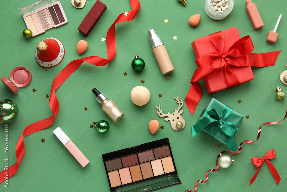 Christmas composition with different makeup products and gift boxes on green background