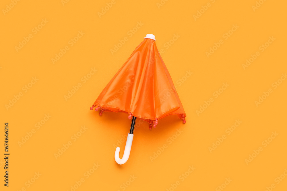 Mini orange umbrella on color background