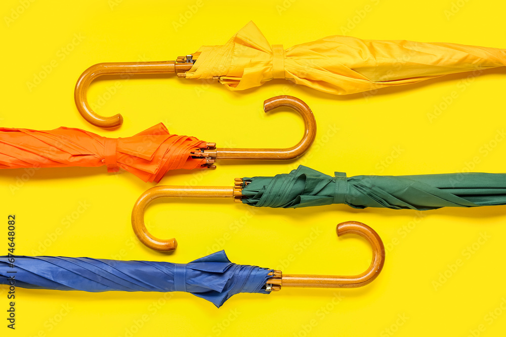 Different stylish umbrellas on yellow background