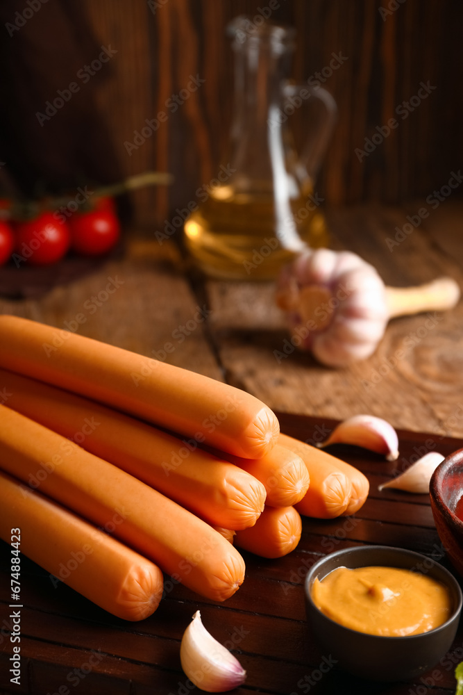 Board of tasty sausages and mustard on wooden background