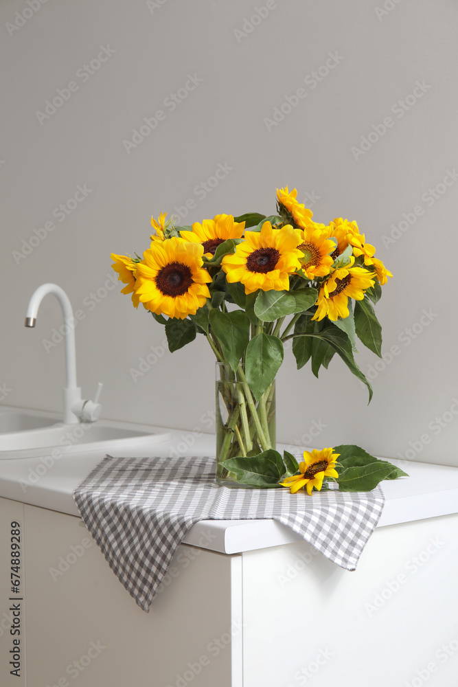 Vase with beautiful sunflowers on white kitchen counter