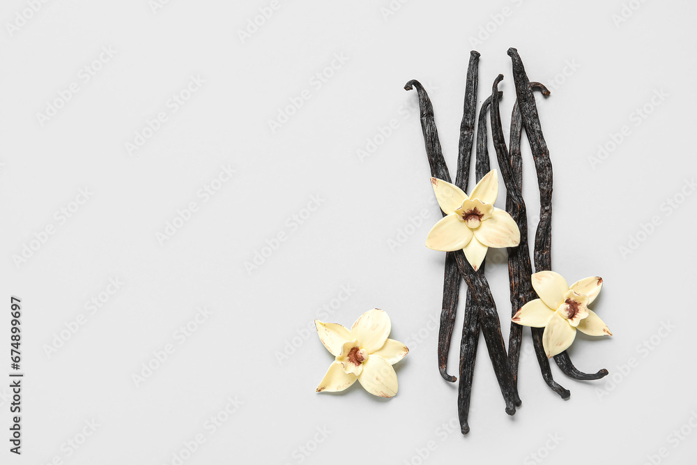 Aromatic vanilla sticks and flowers on grey background