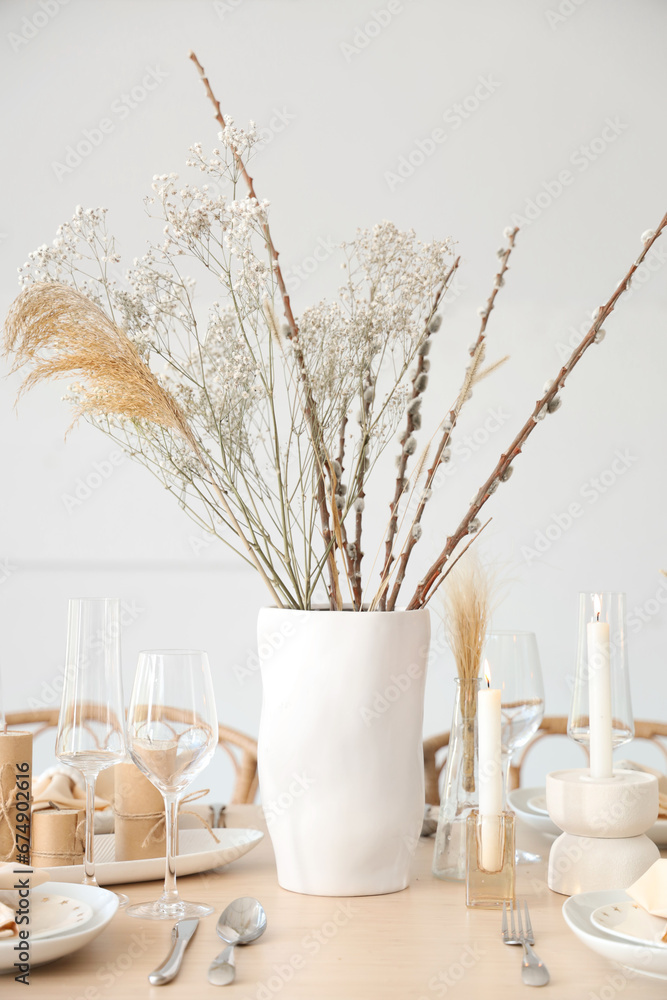 Elegant table setting with candles, dried flowers in vases and glasses