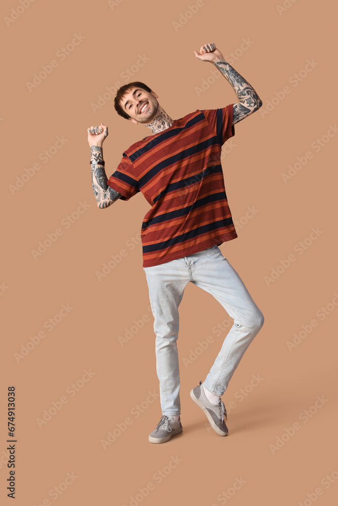 Happy young man dancing on brown background