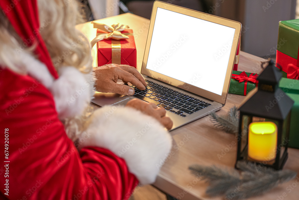 Santa Claus using laptop at table on Christmas eve, closeup