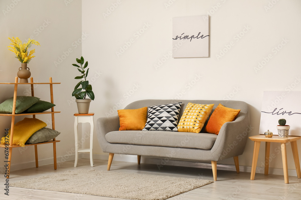 Interior of modern living room with grey sofa, cushions and shelving unit