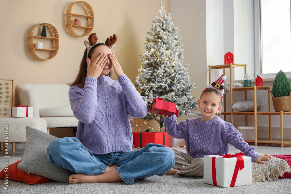 Cute little girl giving her mother Christmas gifts at home