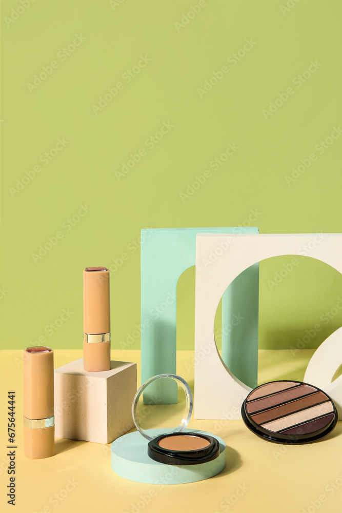 Decorative cosmetics with podiums on table near green wall