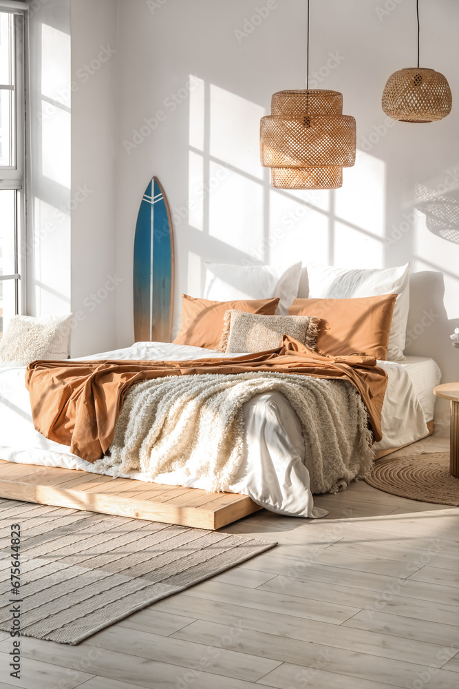 Interior of modern bedroom with surfboard and big bed