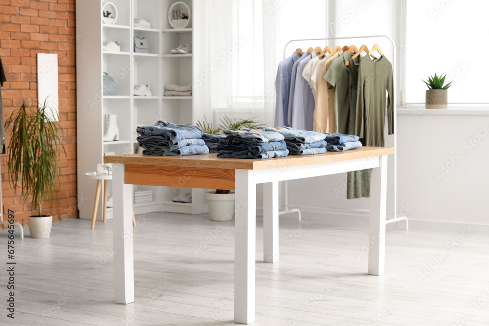 Table with stylish jeans pants in modern boutique