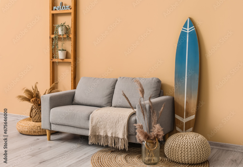 Interior of modern stylish room with surfboard, shelving unit and sofa