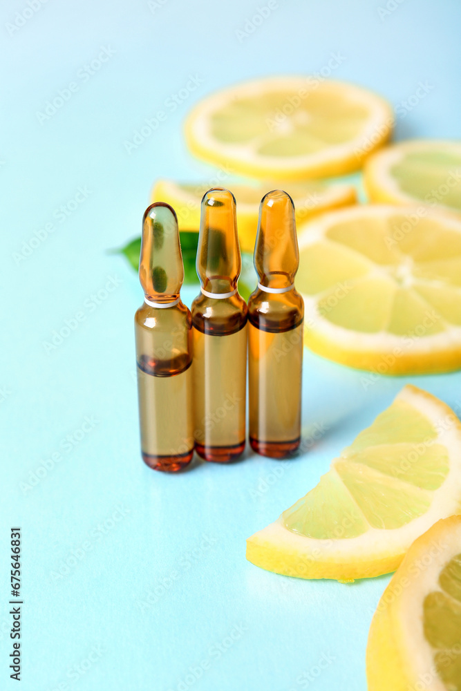 Ampoules with vitamin C and lemon slices on blue background, closeup