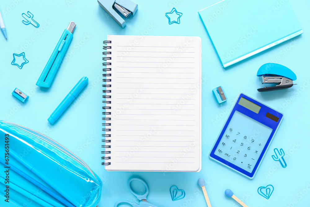 Notebooks and pencil case with different stationery supplies on blue background