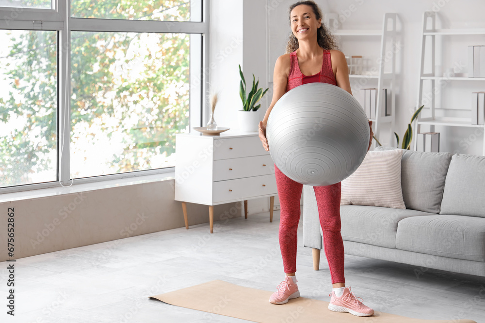 Beautiful adult woman with fitness ball at home