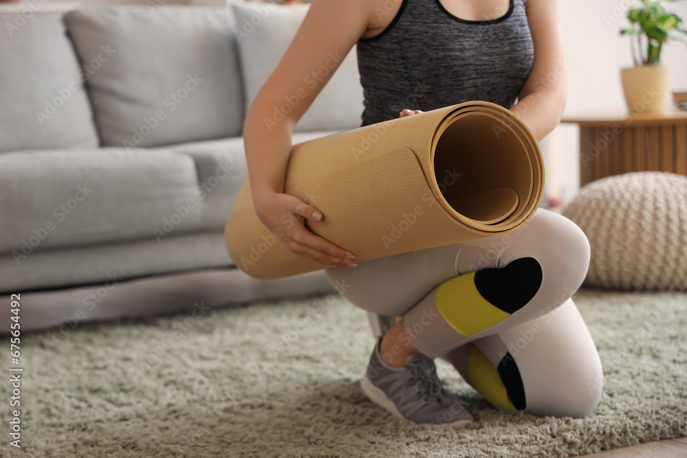 Woman with yoga mat on floor at home