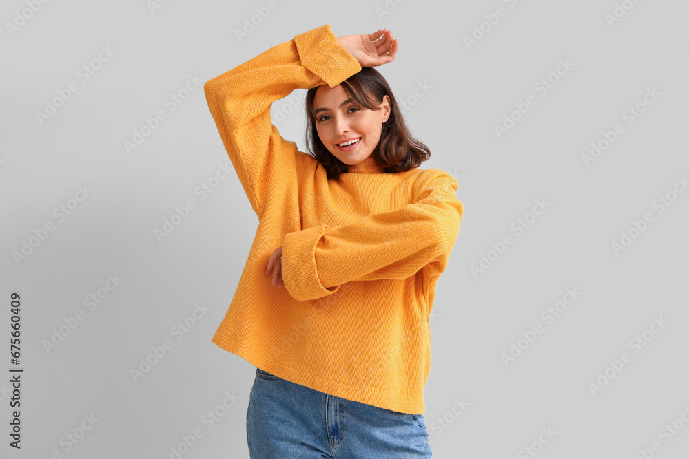 Young woman in yellow sweater on light background