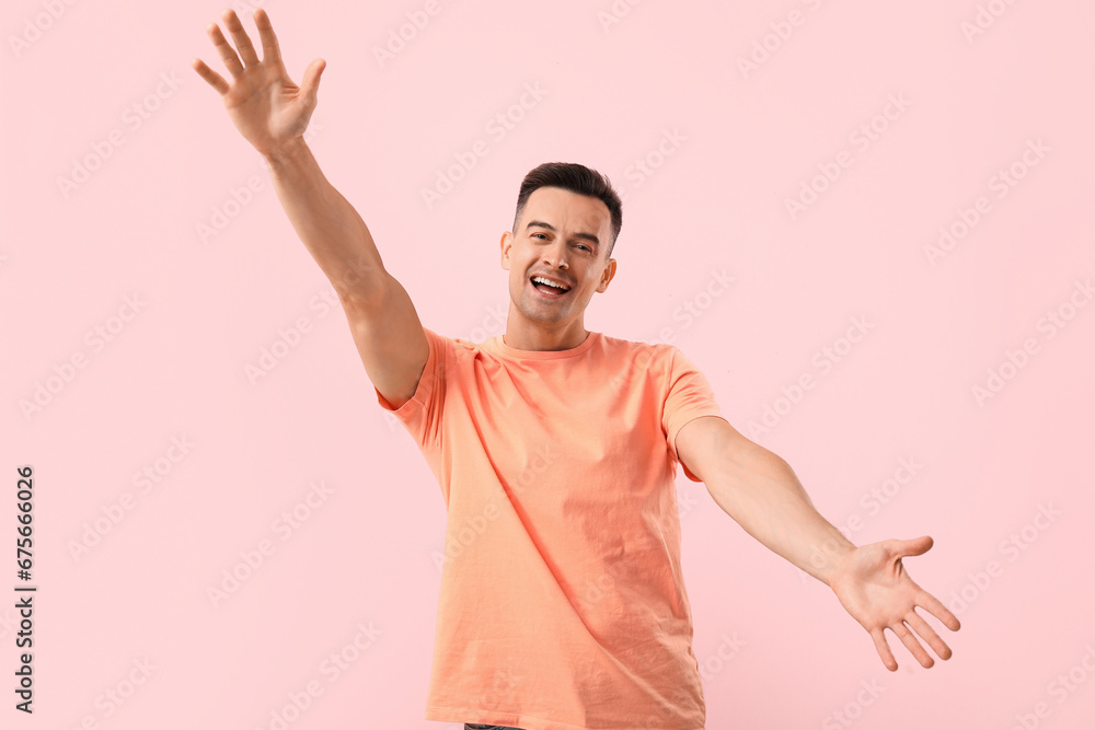 Handsome man opening arms for hug on pink background