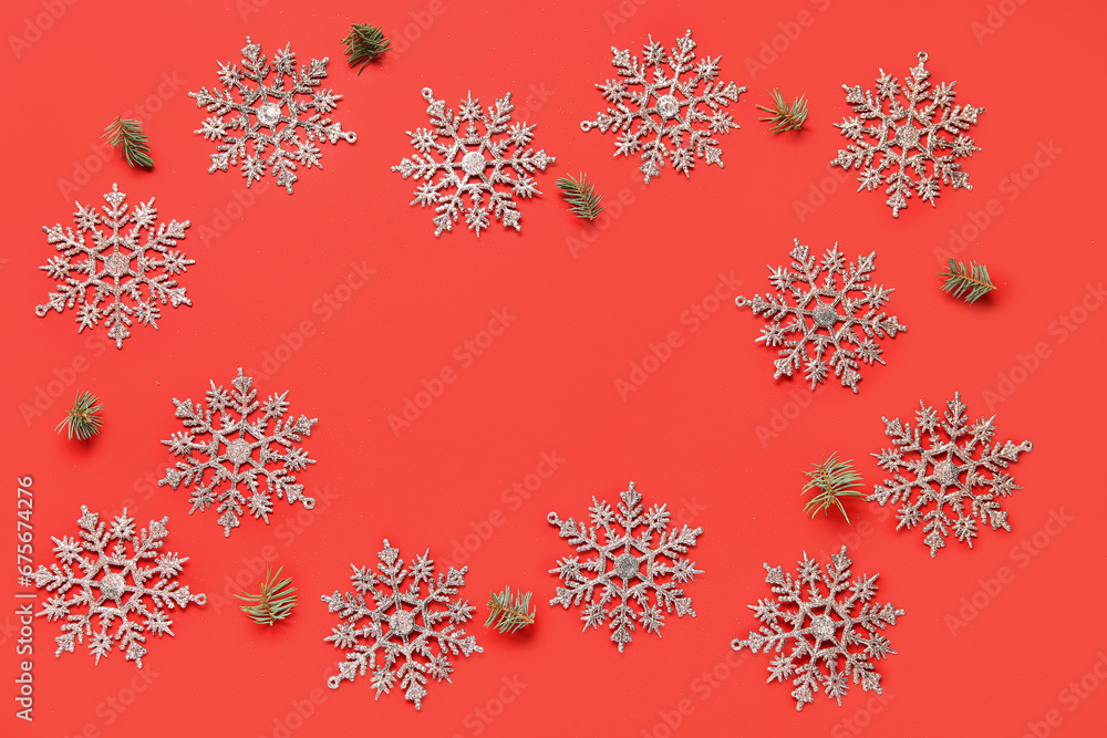 Frame made of beautiful snowflakes with fir branches on red background